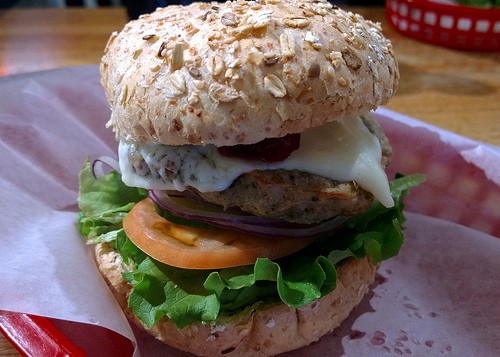 Ground turkey burger on a roll with cheese, lettuce and tomato.