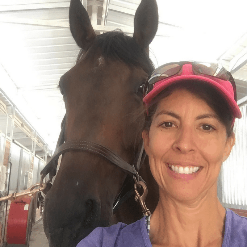 Stephanie smiling next to a horse.