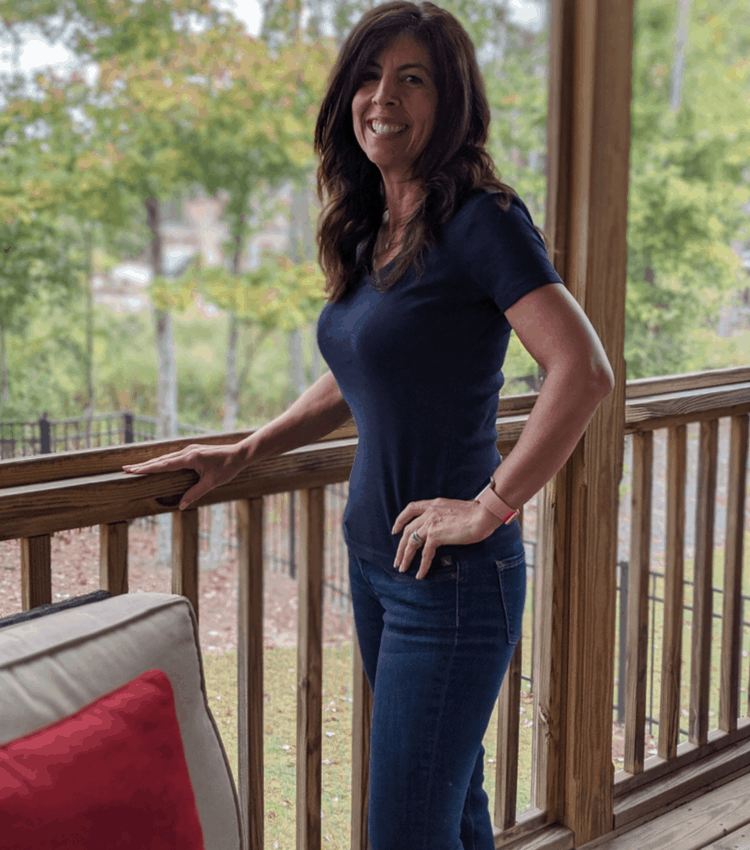 Stephanie standing on porch blue shirt and jeans