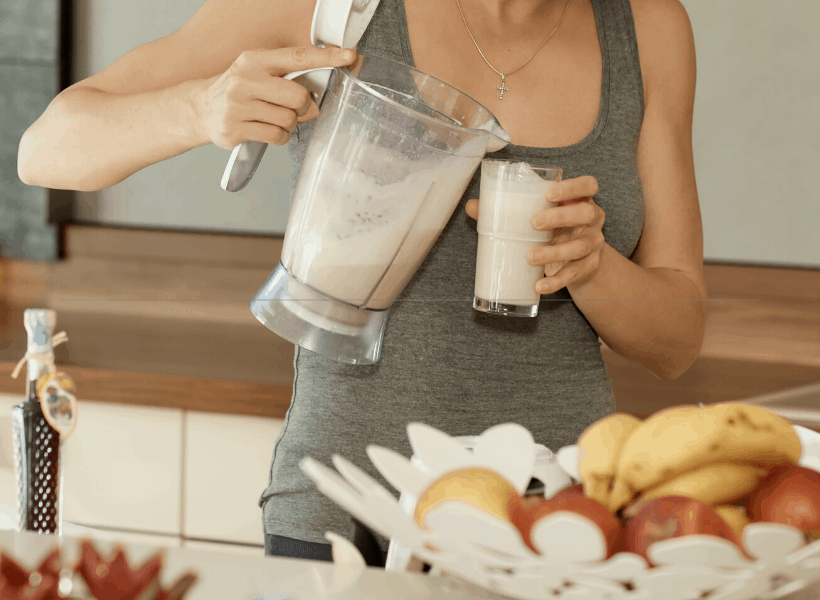 Woman pouring shake from blender into glass.
