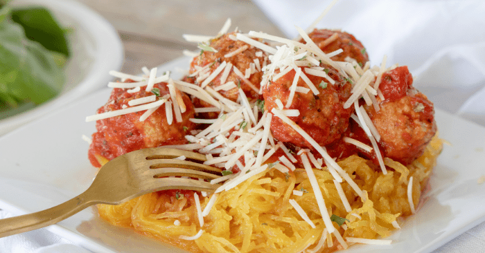 baked meatballs with spaghetti squash on a white plate with a fork