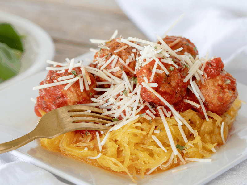 spaghetti squash with turkey meatballs and sauce on white plate with fork