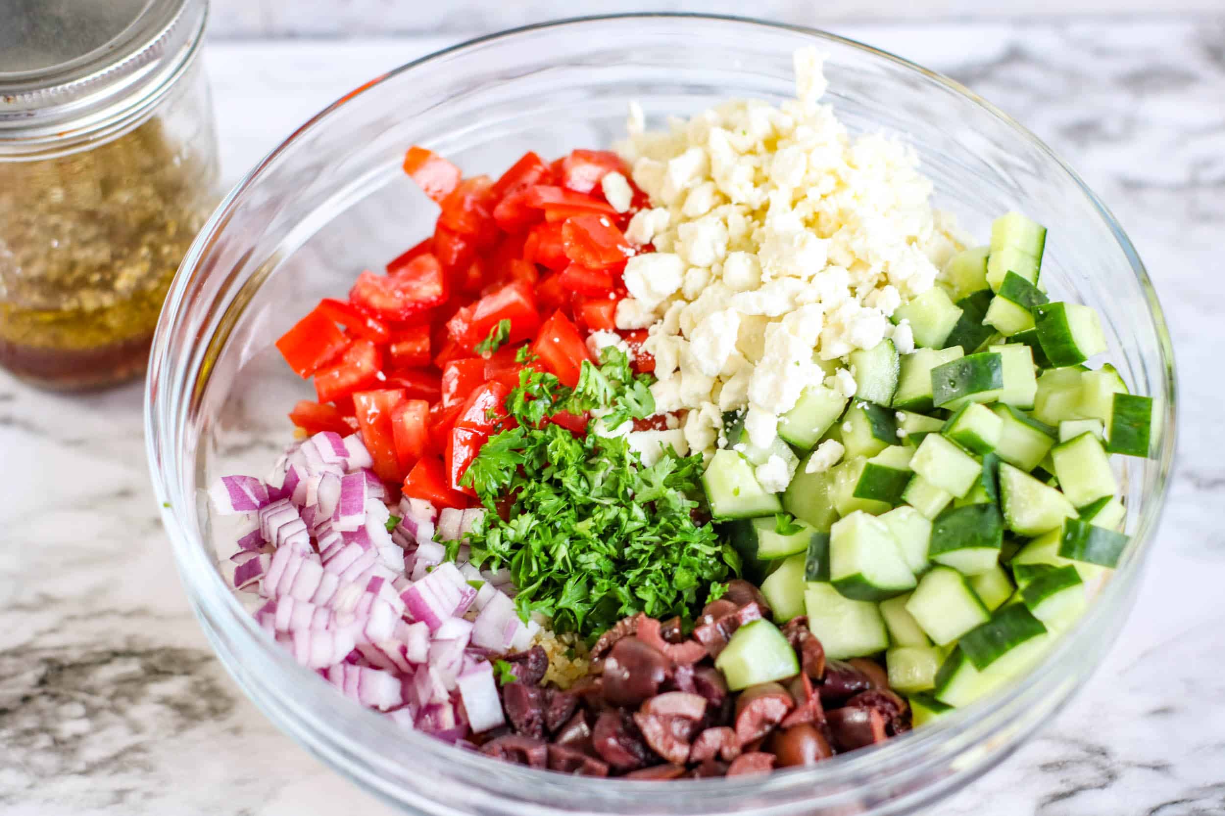 ingredients for greek salad red onion, cucumber, tomato, olives, and quinoa