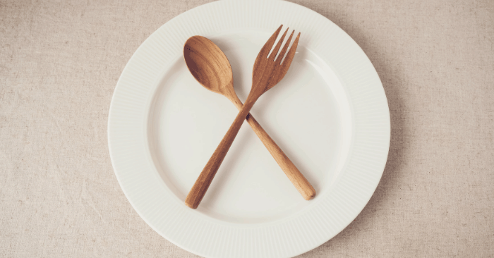 empty plate with fork and spoon laying on top during intermittent fasting