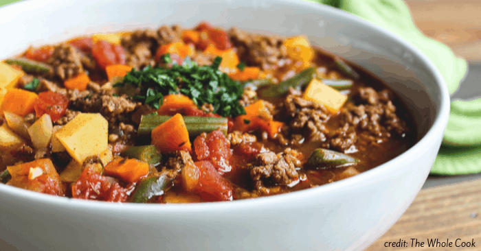 a white bowl of ground beef soup with vegetables