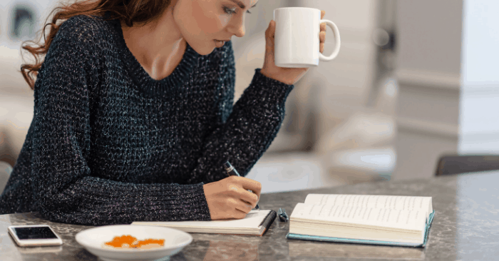 woman sitting at table writing down notes to start keto diet