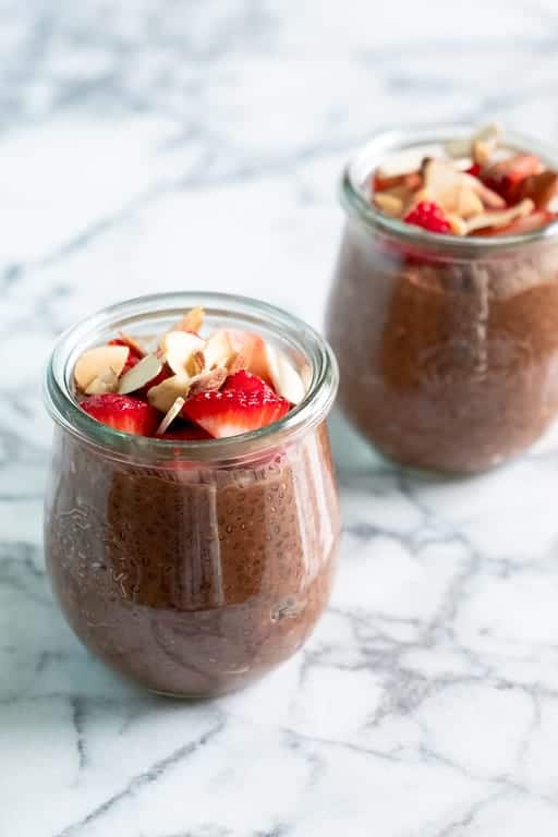 chocolate chia seed pudding in 2 clear jars with fresh strawberries on top