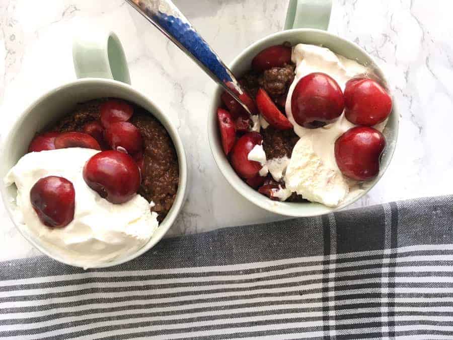 cherry cocoa chia pudding in 2 bowls with cherries and vanilla ice cream as garnish