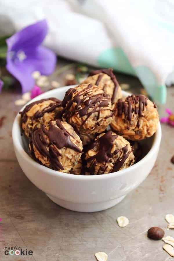 energy balls in a white bowl with chocolate drizzled on top