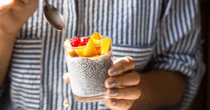 woman holding glass with soaked chia seeds and fruit