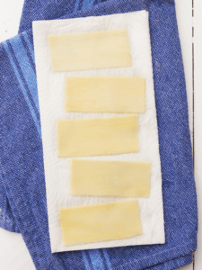 sheets of palmini pasta laying on paper towels to dry after soaking milk
