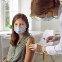 Vaccination,Of,Children.,Smiling,Child,In,Protective,Mask,Receiving,Vaccine