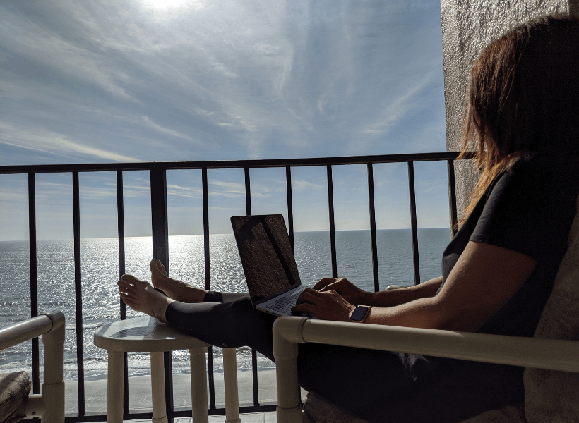 lady on laptop on balcony at the beach