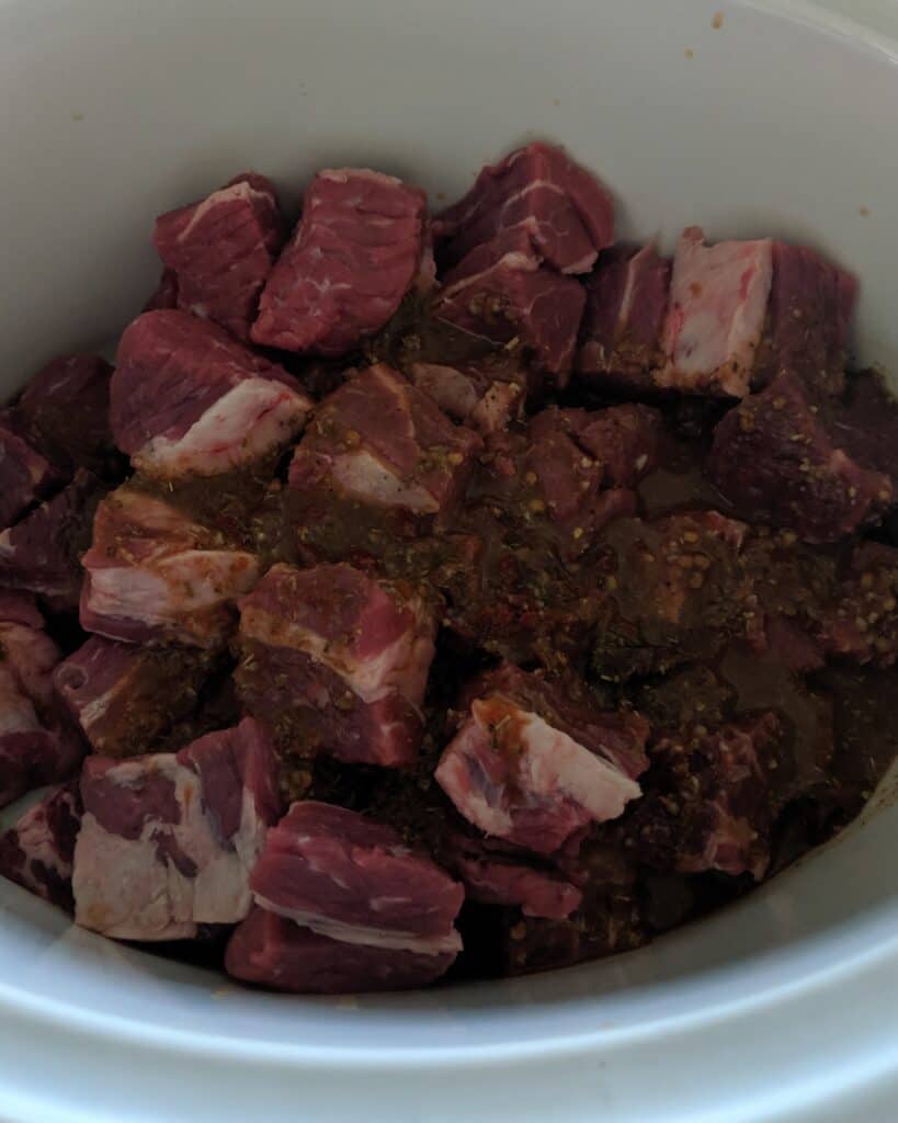 cut chuck roast with sauce in crock pot to be cooked