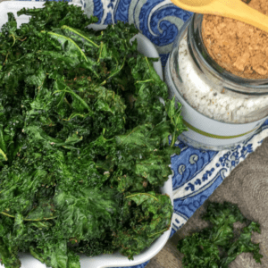 bowl of crispy kale chips with seasoning after baked in oven