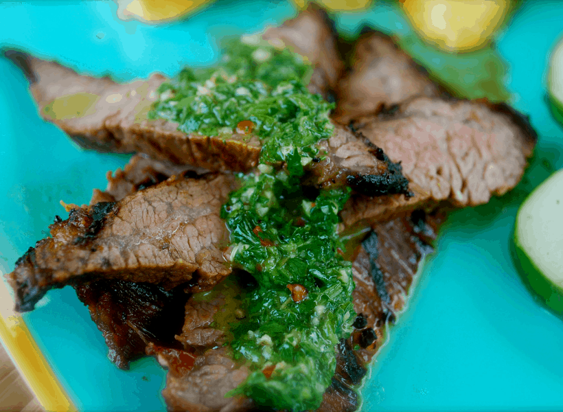 sliced flank steak with chimichurri sauce on plate