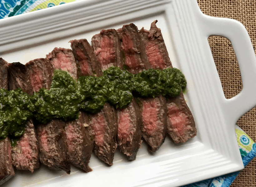 flank steak with chimichurri on a plate