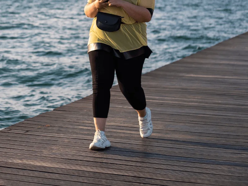overweight lady walking by water on pier