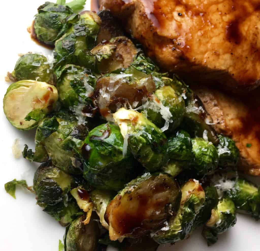 Brussels Sprouts on a white plate next to pork chops