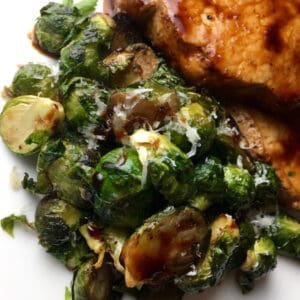 Brussels Sprouts on a white plate next to pork chops