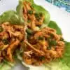 buffalo chicken in lettuce cups on a white plate with a blue decorative background