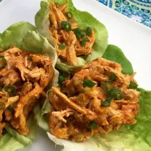 buffalo chicken in lettuce cups on a white plate with a blue decorative background