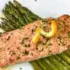 orange glazed salmon over asparagus on a white plate