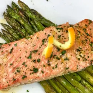 orange glazed salmon over asparagus on a white plate