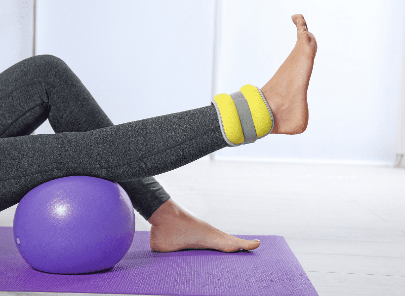 lady exercising on yoga ball lifting leg with ankle weight 