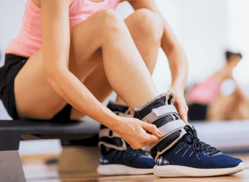 lady with shorts strapping ankle weights around ankle