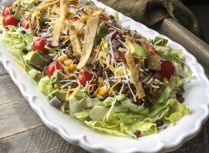 beef taco salad on a white plate with a brown tray