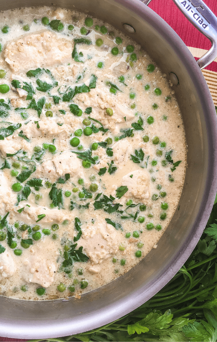 creamy quinoa with chicken and peas in a skillet