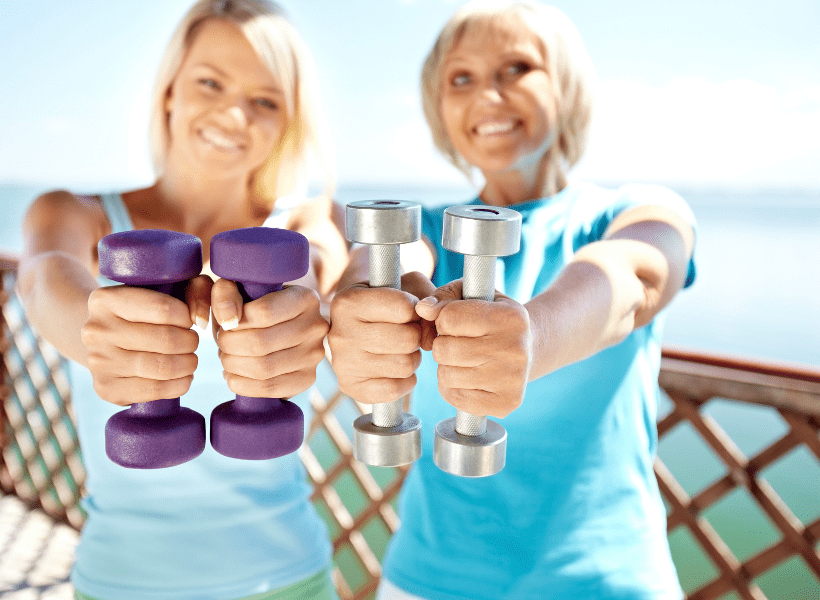 2 women holding hand weights silver medal and purple neoprene dumbbells out to show us
