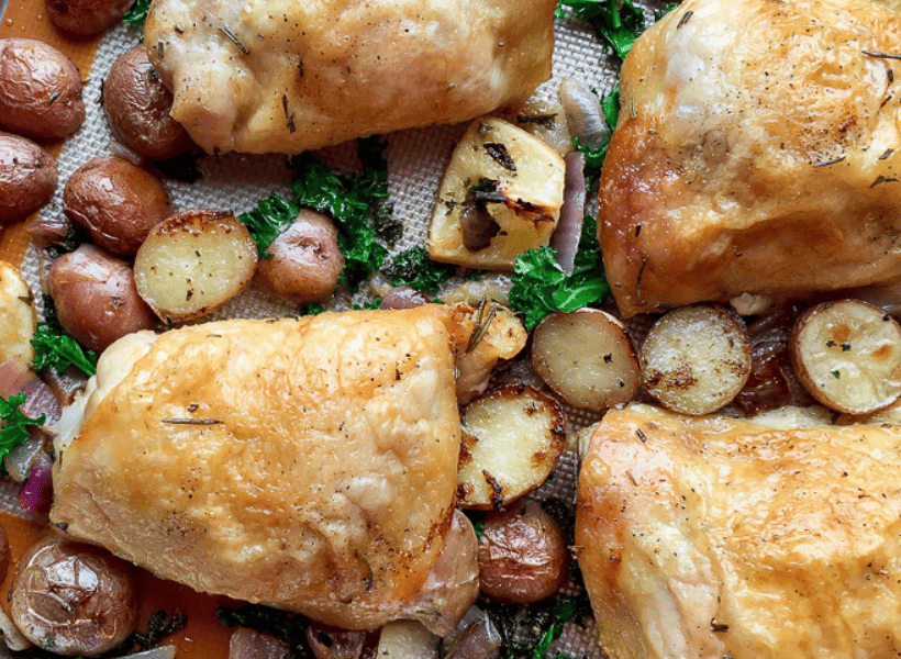 browned baked chicken thighs on sheet pan with herbs, red potatoes halved and sliced red onions