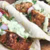 three fish tacos with blackening and creamy dressing in soft taco shells
