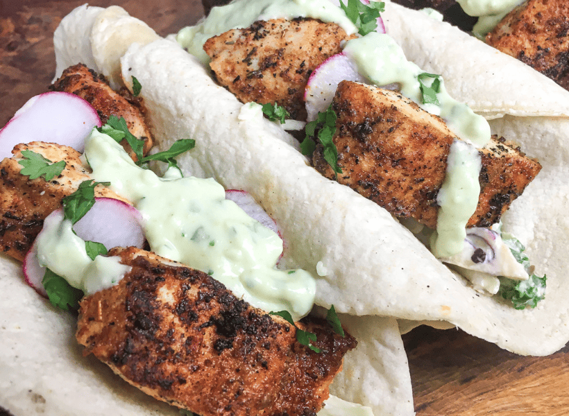three fish tacos with blackening and creamy dressing in soft taco shells