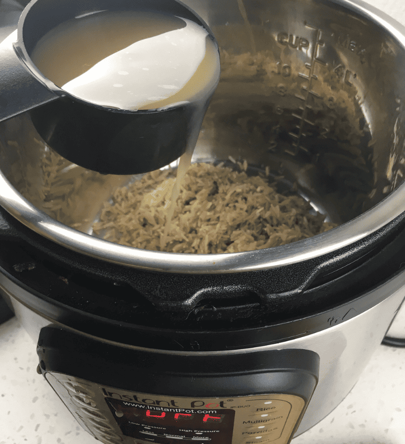 instant pot with brown rice inside and broth being poured in