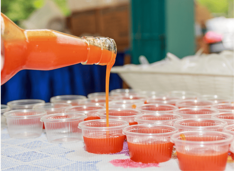 Red sriracha sauce being poured into small plastic containers.
