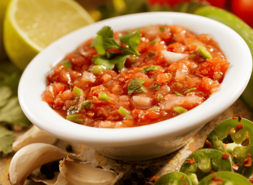 White bowl of fresh salsa with cilantro on top.