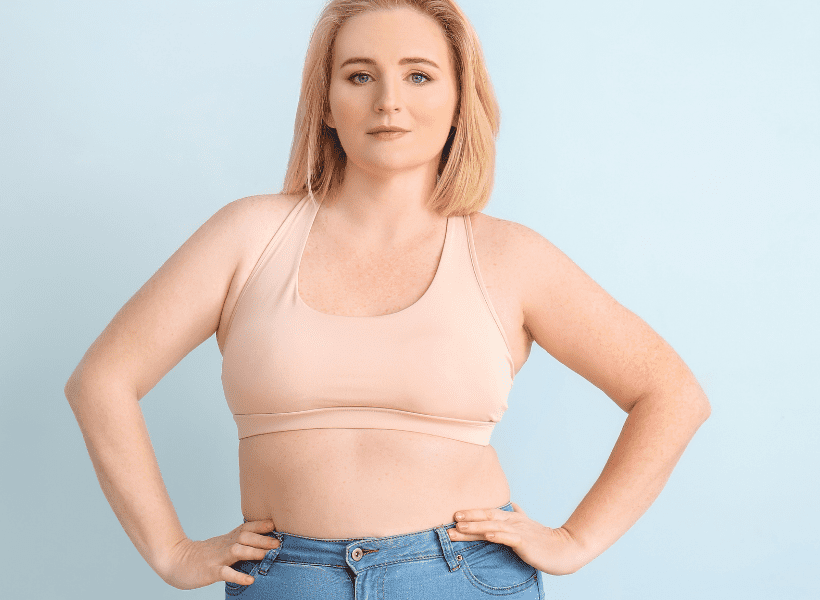 woman in jeans and neutral sports bra with hands on hips