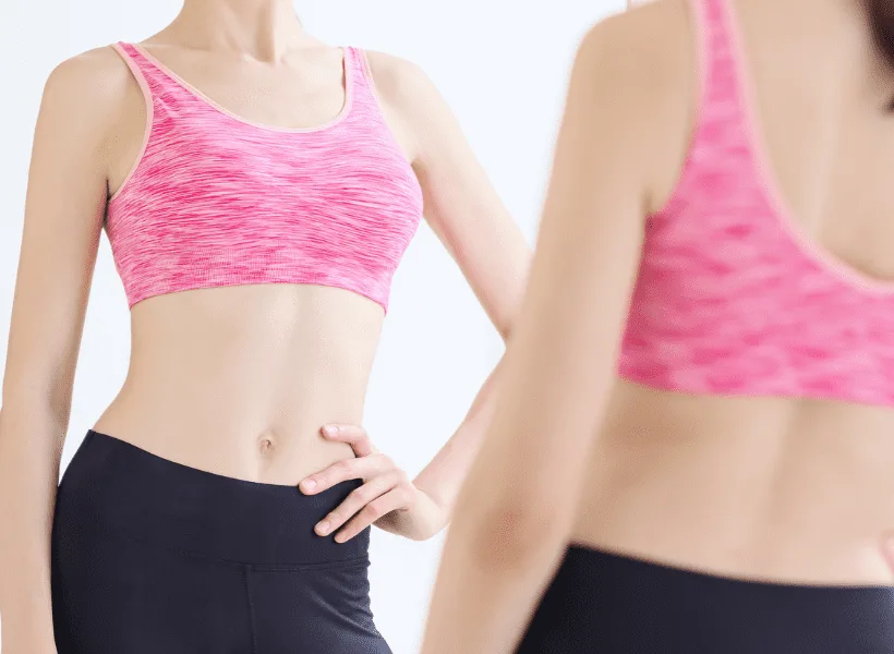 lady in pink sports bra and black leggings looking in mirror