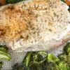 seasoned boneless pork chop on sheet pan with cooked broccoli