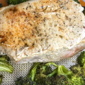 seasoned boneless pork chop on sheet pan with cooked broccoli