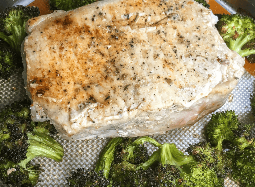 seasoned boneless pork chop on sheet pan with cooked broccoli