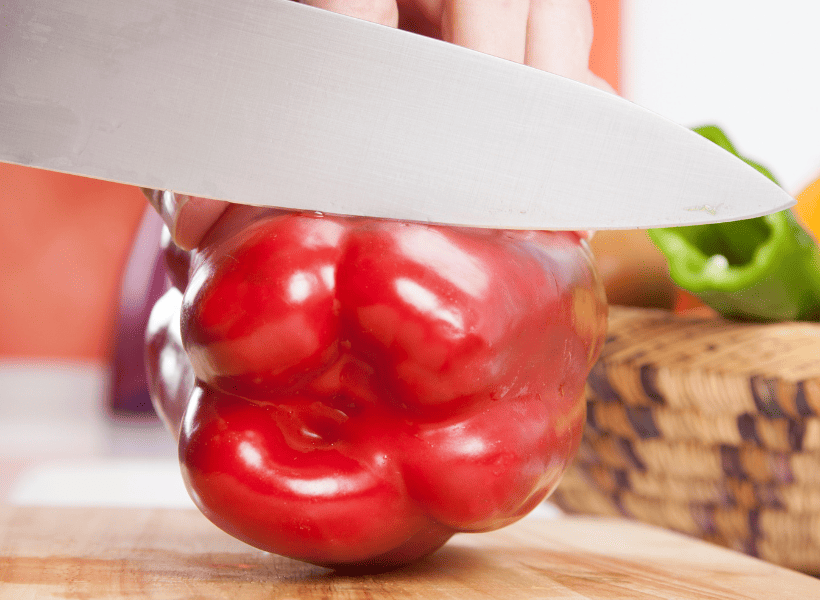 red pepper on cutting board with knife slicing