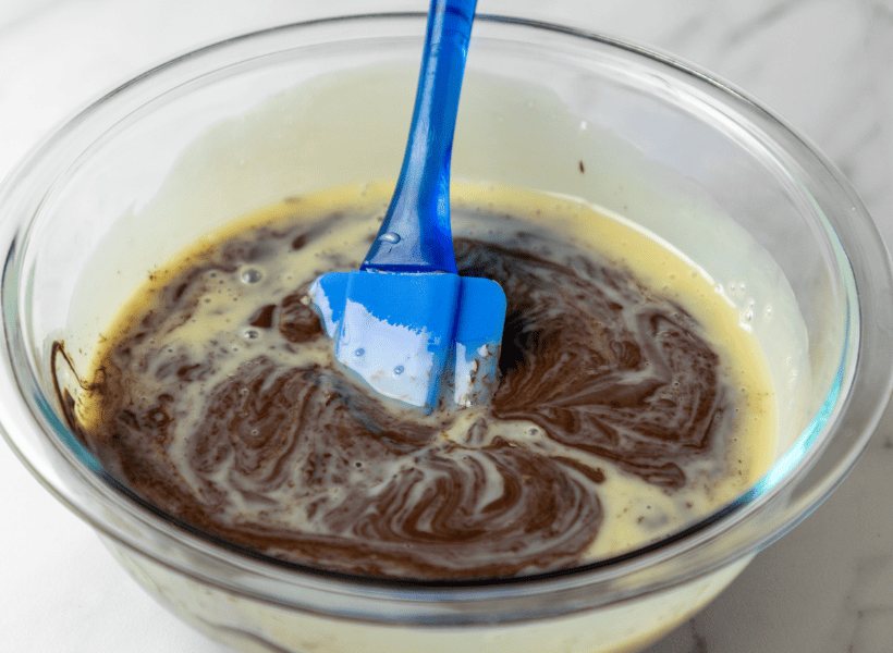 melted chocolate chips and sweetened condensed milk in glass bowl with blue spatula