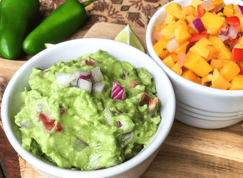 guacamole with red onions garnish in white bowl, mango salsa in white bowl