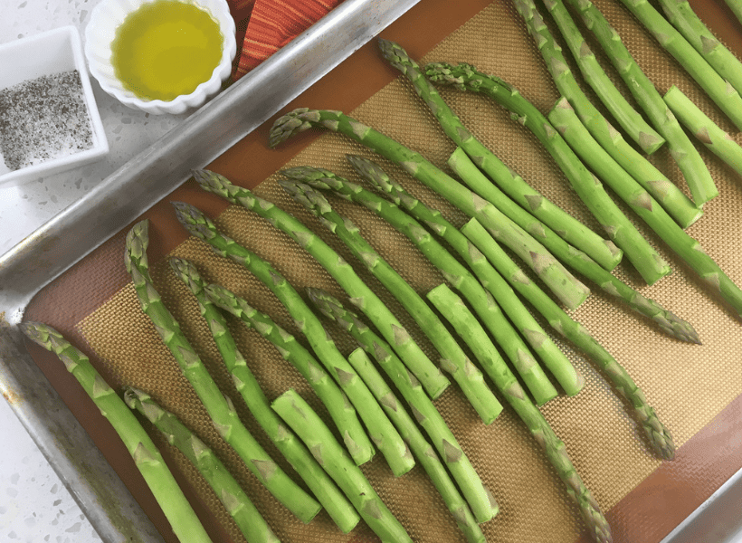 raw asparagus on baking sheet