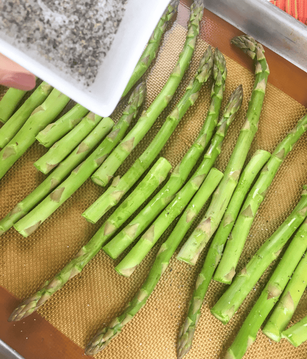 fresh asparagus with olive oil and salt and pepper on baking sheet