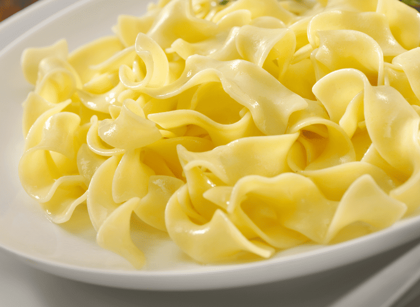 white bowl of cooked wide egg noodles